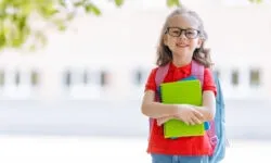 Kind mit Schulranzen vor der Schule