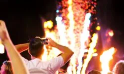 Frau fotografiert Feuerwerk mit Smartphone.